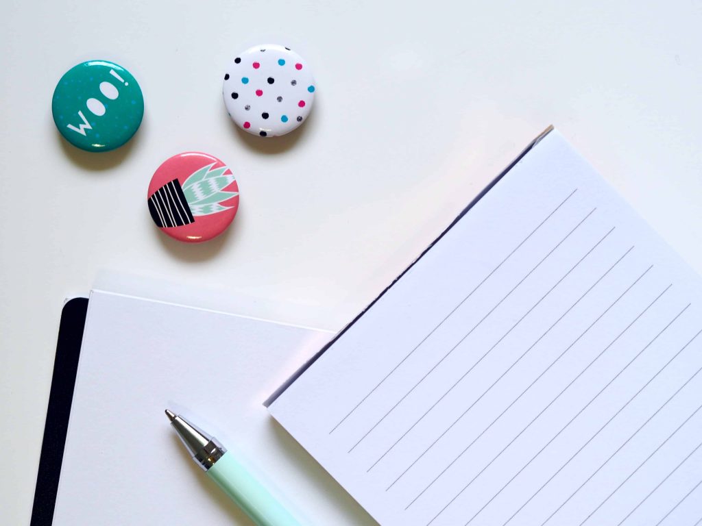 flat lay of 3 magnets, pad of lined paper and a pen