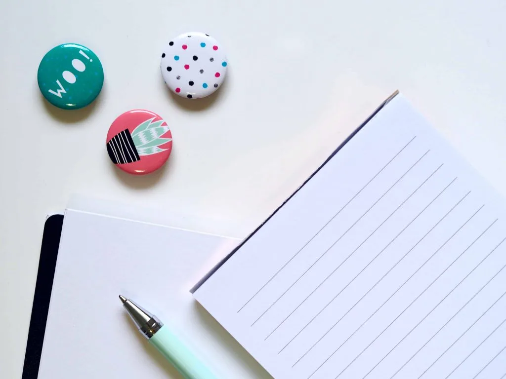 flat lay of 3 magnets, pad of lined paper and a pen