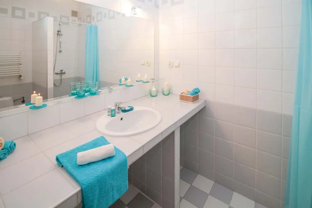 picture of white and gray bathroom with turquoise shower curtain and towels