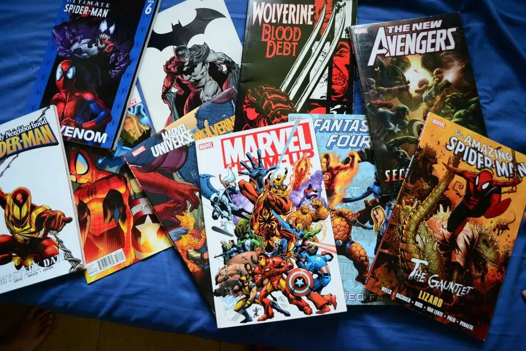 assortment of comic books laying on a bed