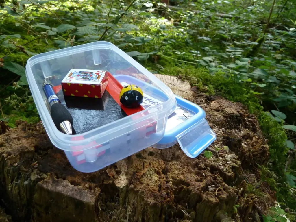 geocaching treasure box with a pokemon ball, pen, playing cards