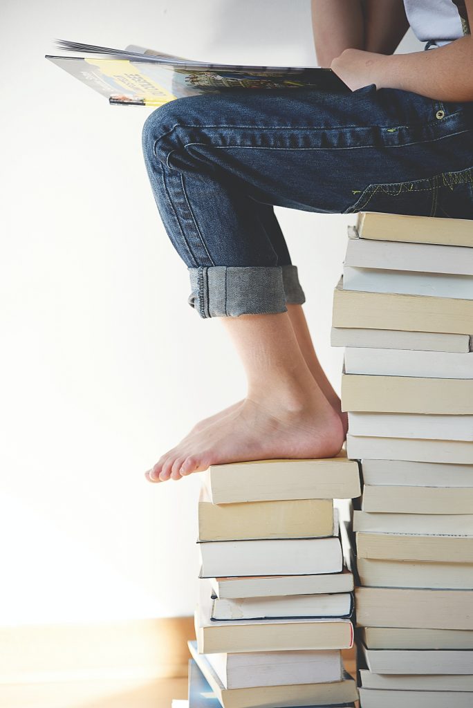 stack of books with kid sitting on them