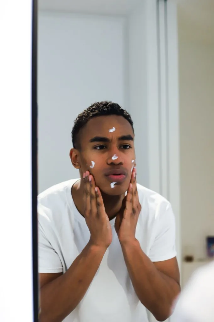 boy in mirror with shaving cream on his face when does facial hair start growing