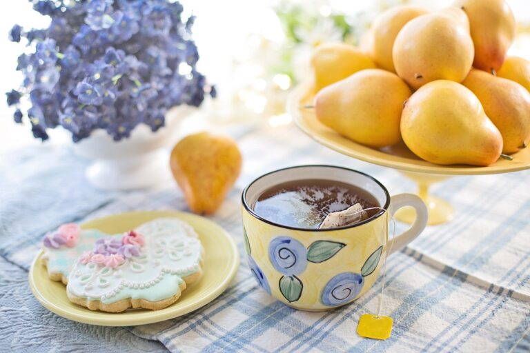 table setting with a full tea cup, butterfly shaped cookie, bowl of lemons and vase with lavender flowers