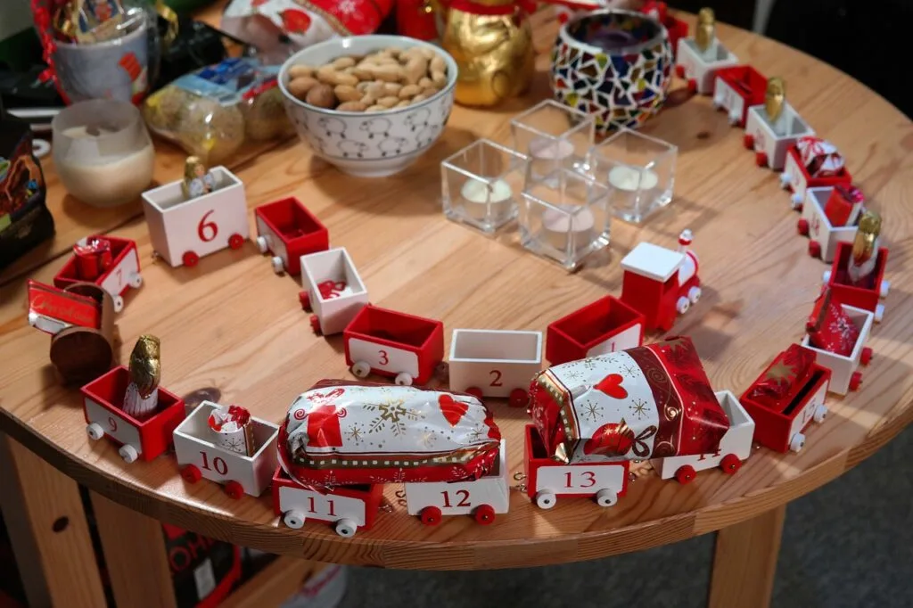 wooden red and white train cars labeled with numbers to use for advent calendar. cars have small gifts in each. displayed on table