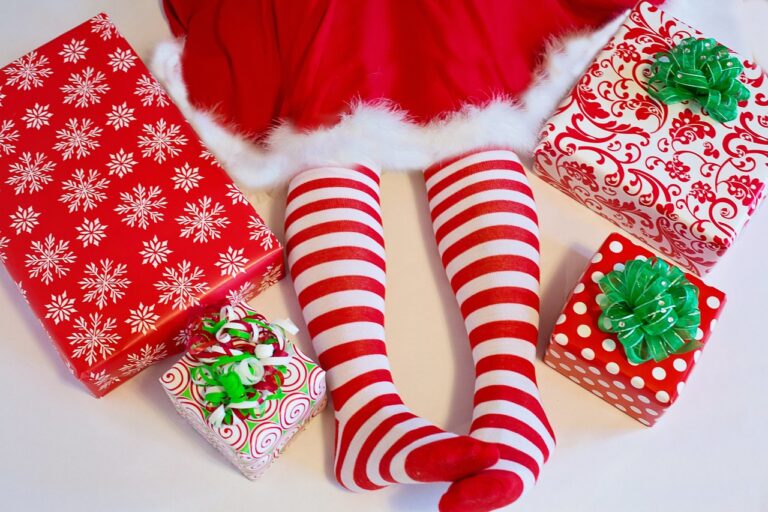 Elf dress or Mrs Santa dress hem showing with legs wearing red and white striped stockings, no shoes 4 gifts wrapped in red and white wrapping paper with green bows are next to the legs
