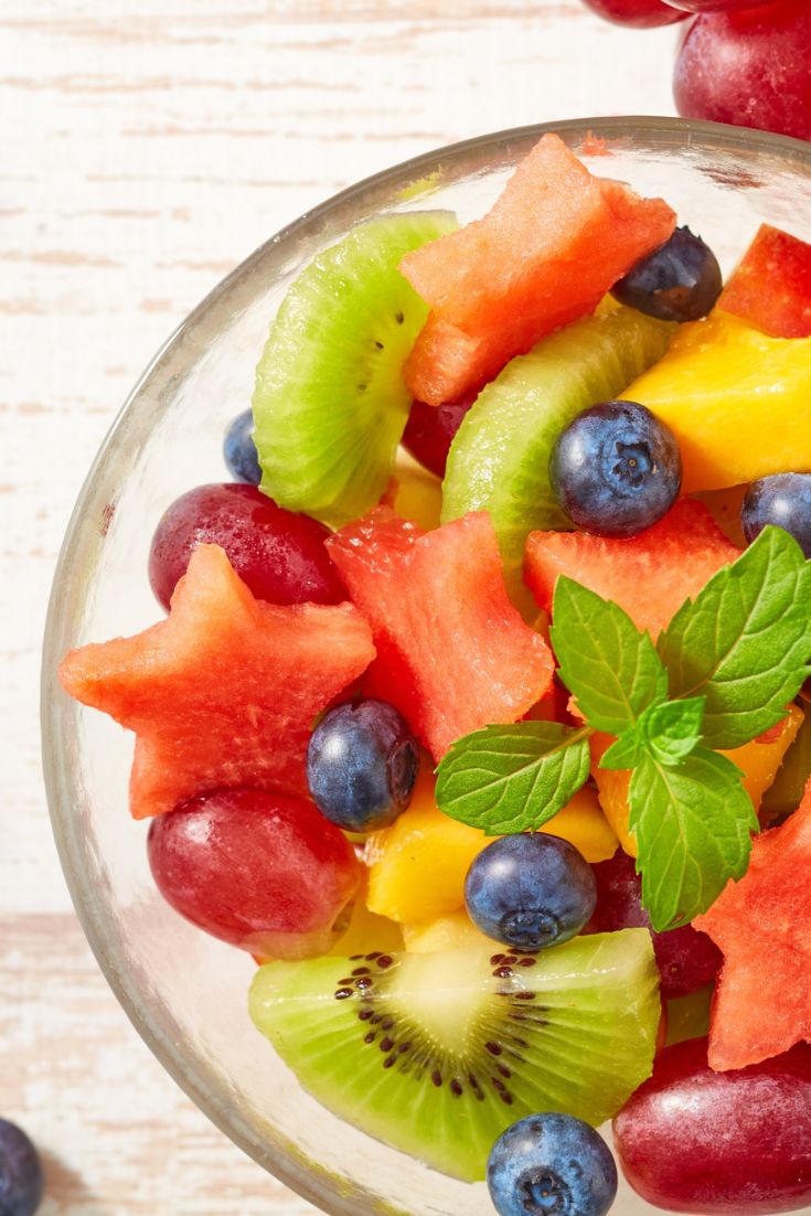 fruit salad in a bowl. kiwi, bluberries, red grapes, mango, watermelon cut in stars, mint sprig on top. summer salad ideas